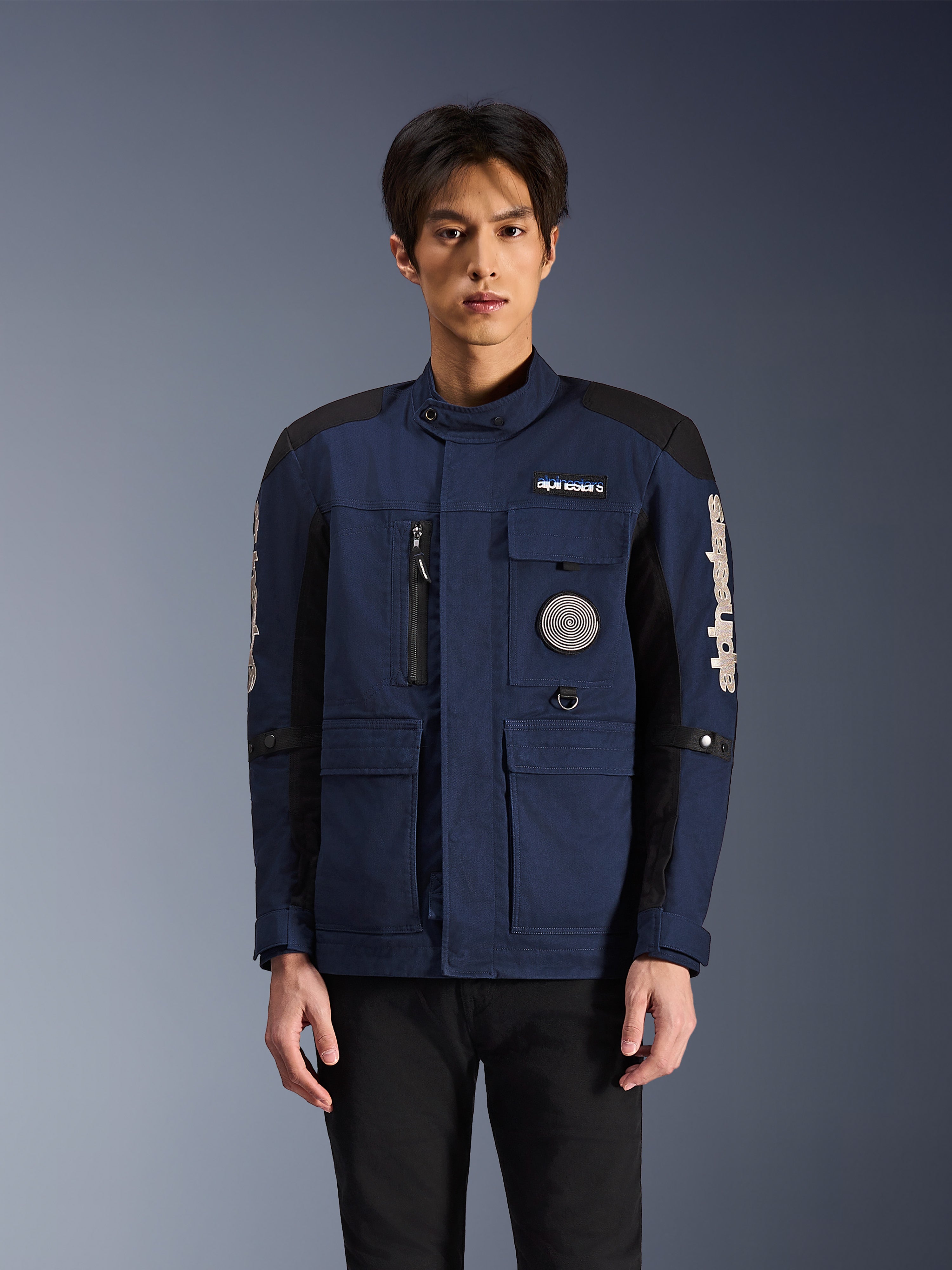 Alpinestars Dice Jacke, Urbane Motorradjacke, Dunkelblau und Schwarz, Multi-Pocket-Fieldjacket-Design mit Spiral-Patch auf der Brust und weißem Alpinestars-Branding auf den Ärmeln, moderne von Workwear inspirierte Motorradbekleidung