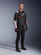 Alpinestars T-Sps Air V2 Jacket, Black White Red Fluo, worn by a male model with black riding pants and gloves, textile motorcycle jacket featuring large mesh panels, white shoulder and forearm sections, and bold Alpinestars logo on the chest.