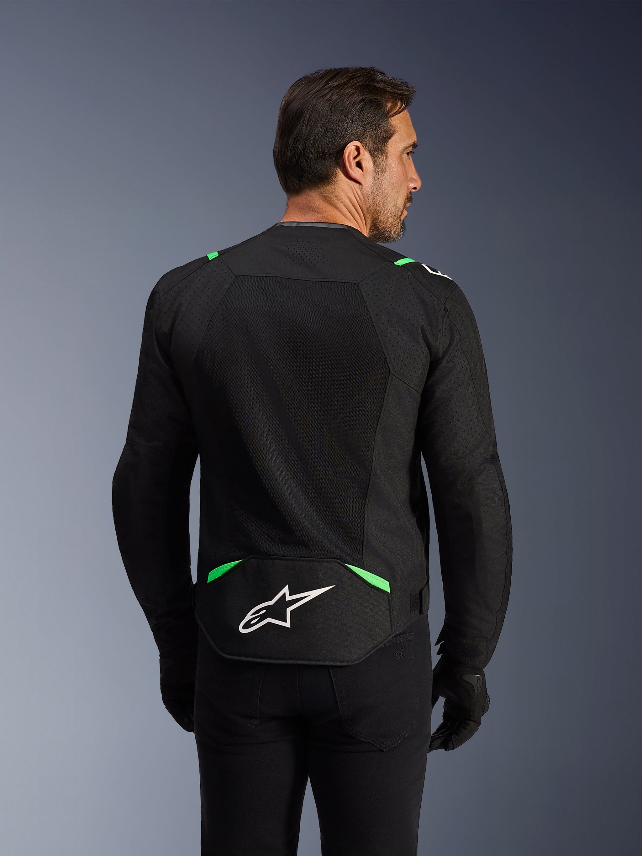 Alpinestars T-SPS Air V2 Jacke, Textil-Motorradjacke, Schwarz und Fluo-Grün, Rückansicht mit großen Tech-Mesh-Einsätzen zur Belüftung, weißes Alpinestars-Logo im unteren Rückenbereich, sportlich-ergonomische Passform für urbanes Fahren