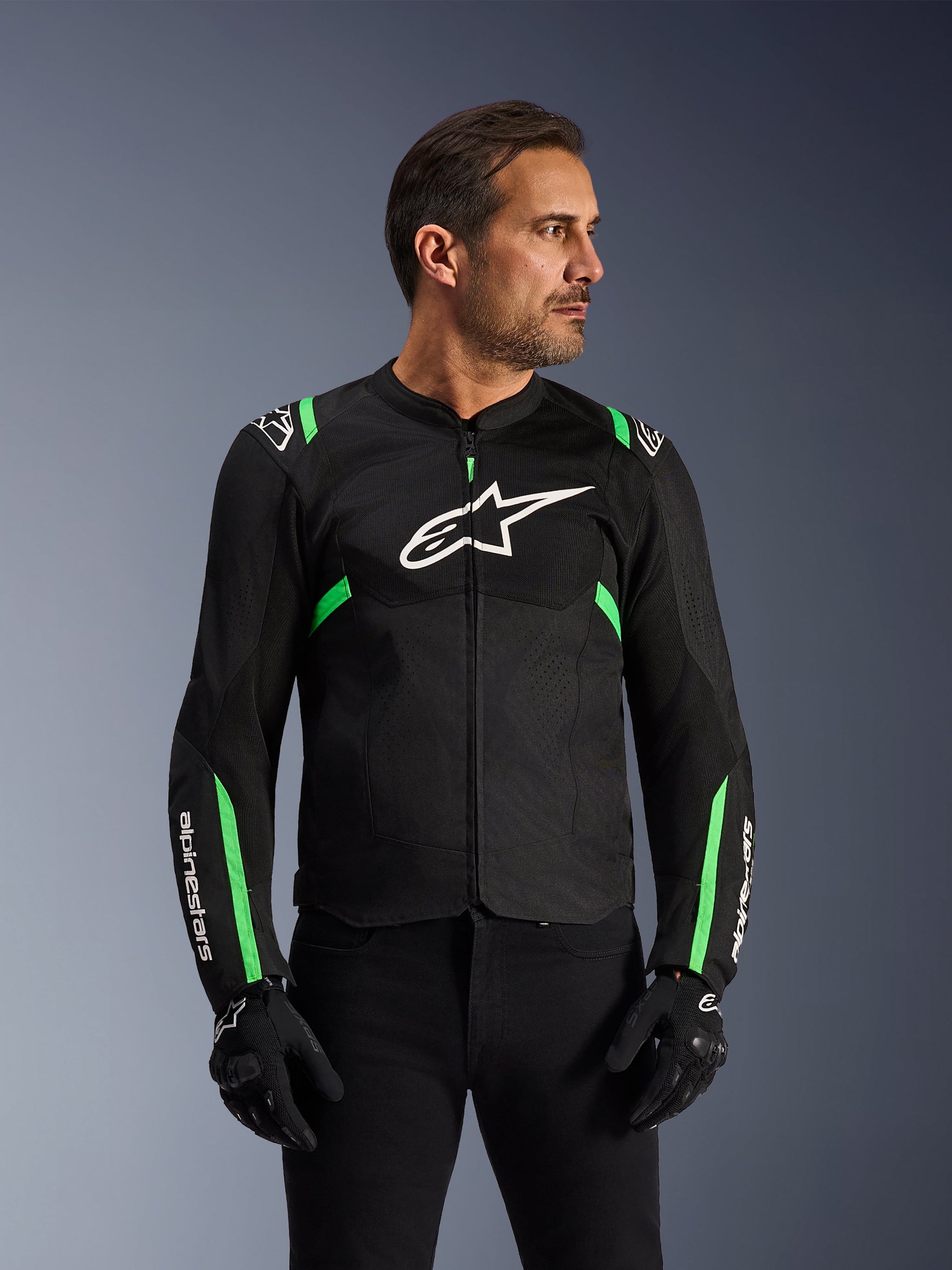 Alpinestars T-SPS Air V2 Jacke, Motorradjacke, Schwarz und Fluo-Grün, getragen von einem Model mit schwarzen Motorradhandschuhen und -hose, weißes Alpinestars-Logo auf der Brust und neongrüne Akzente an Schultern und Ärmeln, Tech-Mesh-Einsätze zur Belüftung, sportlicher Schnitt für urbanes Fahren