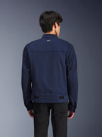 Alpinestars Bruiser Jacke, dunkelblaue Textil-Motorradjacke, Rückansicht am Model, Workwear-inspiriertes Design mit einem kleinen weißen Astars-Logo im Nacken, verstellbare Taillenriegel, moderne urbane Motorradbekleidung