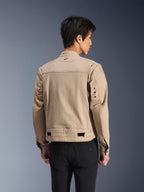 Alpinestars Bruiser Jacke, braune urbane Motorradjacke, Rückansicht mit plissierten Schultern und verstellbaren Taillenriemen, getragen mit schwarzer Hose, moderne, von Arbeitskleidung inspirierte Fahrausrüstung