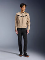 Alpinestars Bruiser Jacke, urbane Motorradjacke in Aluminum, getragen mit schwarzer Hose und schwarzen Sneakern, mit schwarzen Reißverschlusstaschen und einem Druckknopfkragen, zeitgenössisches, von Workwear inspiriertes Design für urbanes Fahren
