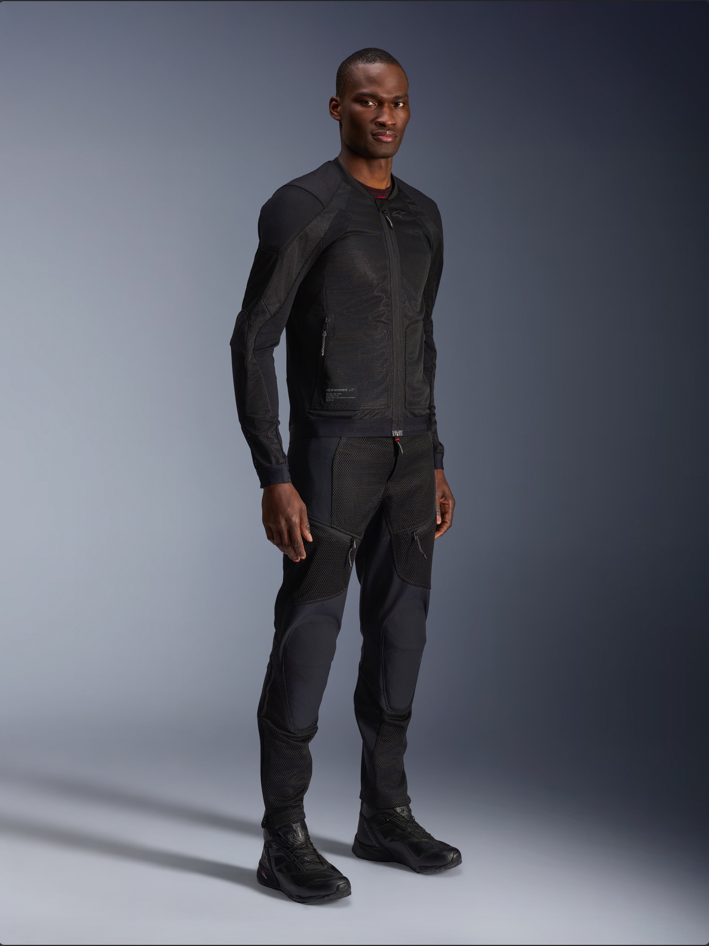 Alpinestars Troop-Air Jacket, Black, technical mesh motorcycle jacket worn by a model with matching black pants and boots, featuring lightweight mesh construction and a minimalist urban design