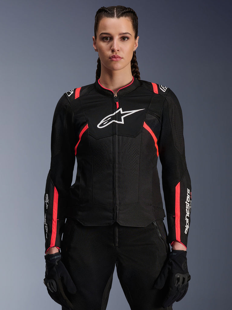 Alpinestars Woman Stella T-Sps Air V2 Jacket, Black and Diva Pink, textile motorcycle jacket featuring breathable mesh panels and pink accents, white Alpinestars logo on chest, worn by a female model with black riding pants and gloves.