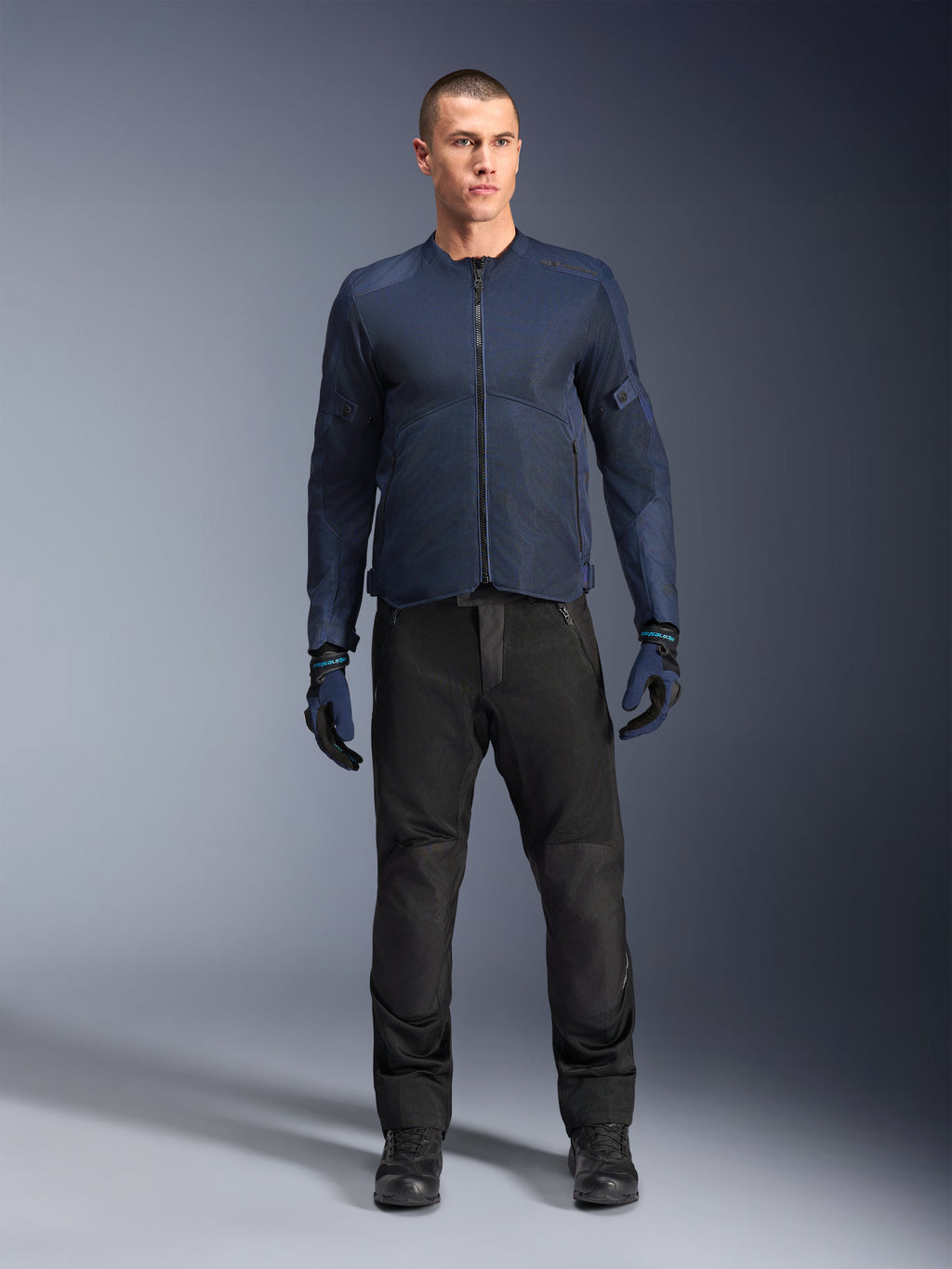 Alpinestars C-1 Air Jacke, urbane Herren-Motorradjacke in Blau aus Tech-Mesh für maximale Belüftung, ideal für Pendeln und Touring, getragen mit schwarzer Hose und blauen Handschuhen.