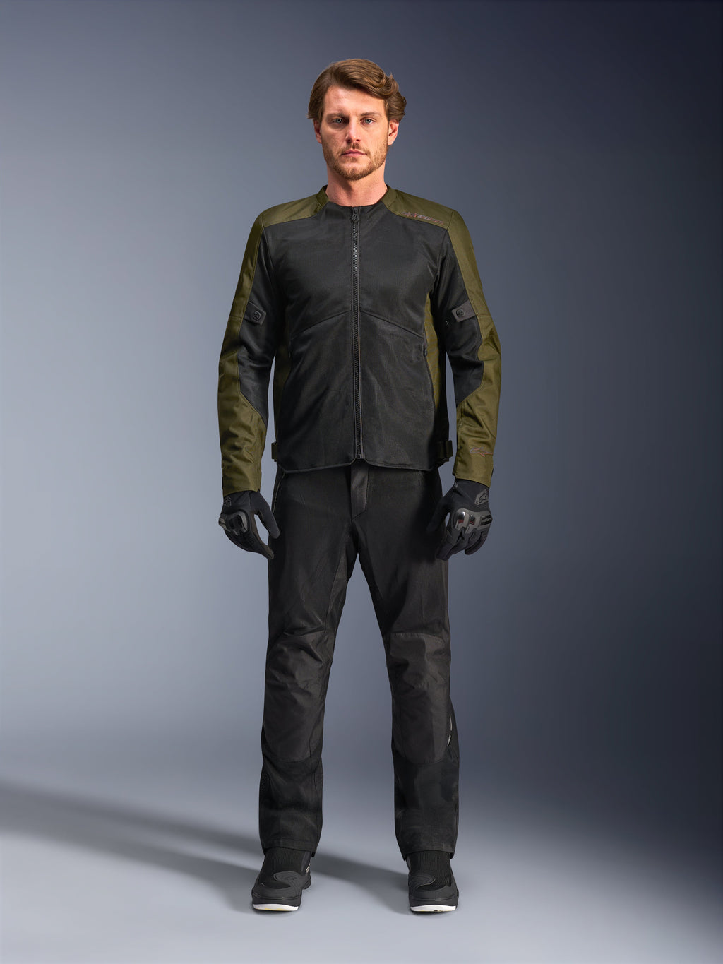 Alpinestars C-1 Air Jacke, Khaki und Schwarz, getragen von männlichem Model mit schwarzer Motorradhose und Handschuhen, leichtes Textildesign mit Tech-Mesh-Einsätzen, moderne urbane Fahrausrüstung