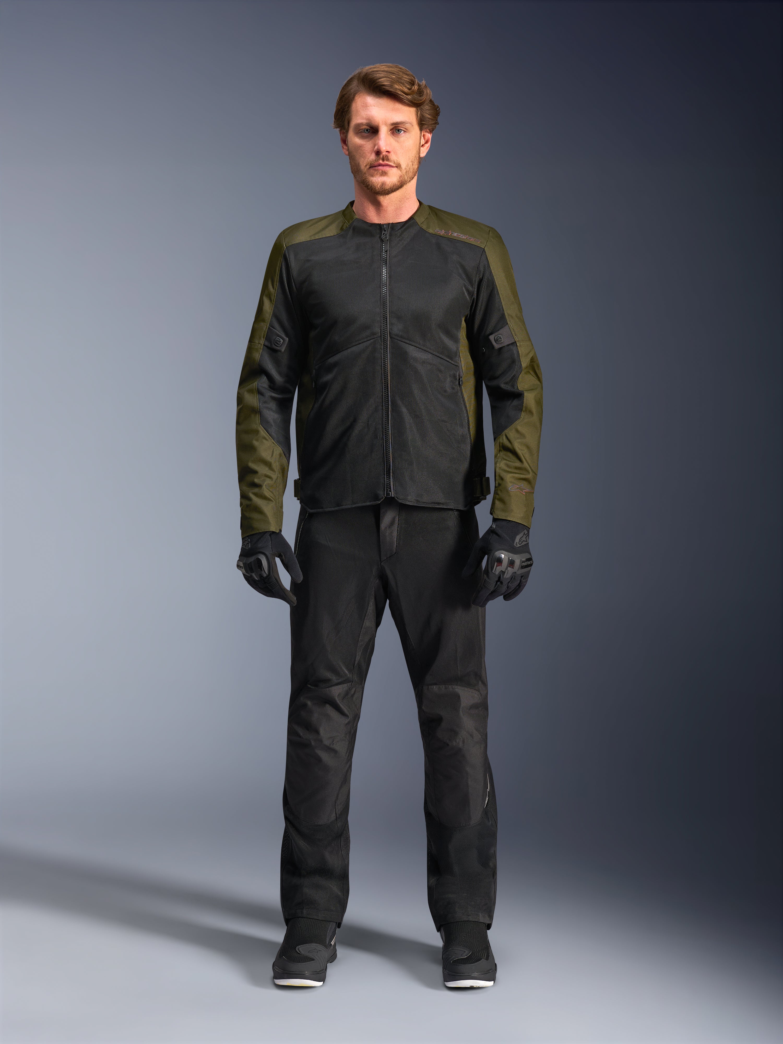 Alpinestars C-1 Air Jacke, Khaki und Schwarz, getragen von männlichem Model mit schwarzer Motorradhose und Handschuhen, leichtes Textildesign mit Tech-Mesh-Einsätzen, moderne urbane Fahrausrüstung