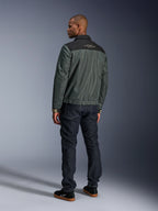 Alpinestars Ignite Air Jacke in Urban Gray Black Blue, Rückansicht am Modell, mit Mesh-Hauptteil, schwarzer Schulterpasse und weißem Text, gestreiften Bündchen, kombiniert mit dunklen Denim-Jeans und schwarzen Sneakern, urbane Lifestyle-Motorradbekleidung