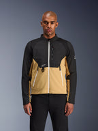Alpinestars Provoke Jacke, Urbane Motorradjacke, Schwarz und Camel, Vorderansicht an einem männlichen Model, zweifarbiges Design mit weißen Reißverschlüssen, Brusttasche mit Reißverschluss und D-Ring, kleines weißes Alpinestars-Logo, moderne urbane Motorradbekleidung