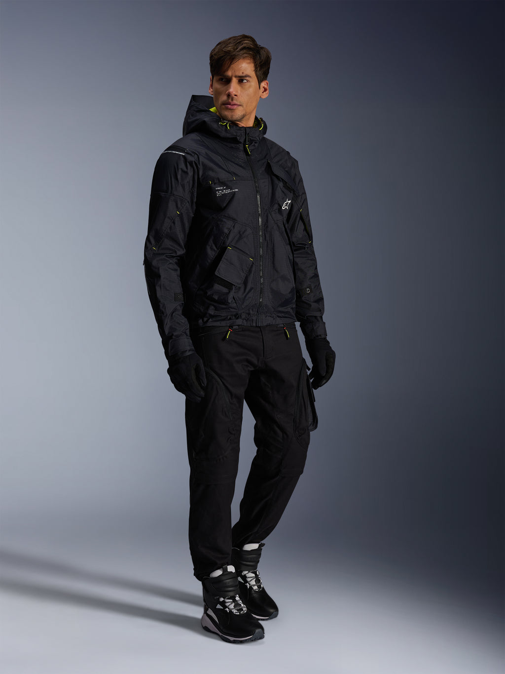 Alpinestars Mogress Air Jacke, Urbane Motorradjacke, Schwarz mit Lime Punch und weißen Akzenten, getragen mit schwarzer Motorradhose, Handschuhen und schwarz-weißen Stiefeln, zeitgenössisches, Utility-inspiriertes Design.