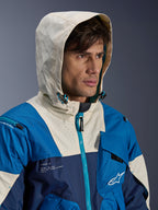Alpinestars Mogress Air Jacket in Blue Almond, urban motorcycle jacket featuring a color-blocked design in blue and cream, model wearing the hood up, lightweight textile construction with technical zipper details.
