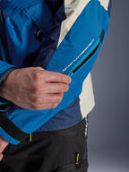 Alpinestars Mogress Air Jacket in Blue Almond, close-up of the sleeve showing the zippered Nucleon Flex protector compartment, technical blue and beige textile with ripstop texture, urban motorcycle apparel detail