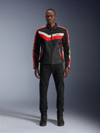 Alpinestars T-Dyno Air Jacke, Textil-Motorradjacke, Schwarz, Hellrot und Ecru, getragen von einem Model mit schwarzer Hose und Stiefeln, Vintage-inspiriertes Design mit markanten Farbstreifen auf der Brust, Stern-Logos an den Ärmeln und atmungsaktiver Mesh-Konstruktion für Fahrten in der Stadt.