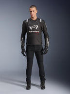 Alpinestars T-Stunt Air Jacke, schwarz-weiße Motorradjacke, getragen mit schwarzer Fahrhose, Handschuhen und Stiefeln, markantes weißes Alpinestars-Branding auf Brust und Ärmeln, sportliches Textildesign mit Mesh-Einsätzen zur Belüftung