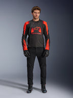 Alpinestars T-Stunt Air Jacket, Black Red Fluo and Dark Red, worn by a model with black riding jeans and gloves, featuring a modular 2-in-1 design with prominent mesh panels for airflow, sport-cut motorcycle gear for road riding
