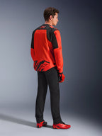 Alpinestars MM93 T-SPS Air V2 Jacket in Red Fluo and Black, back three-quarters view on a model, featuring Marc Marquez 93 branding on the collar and lower back, styled with black pants and red motorcycling shoes.