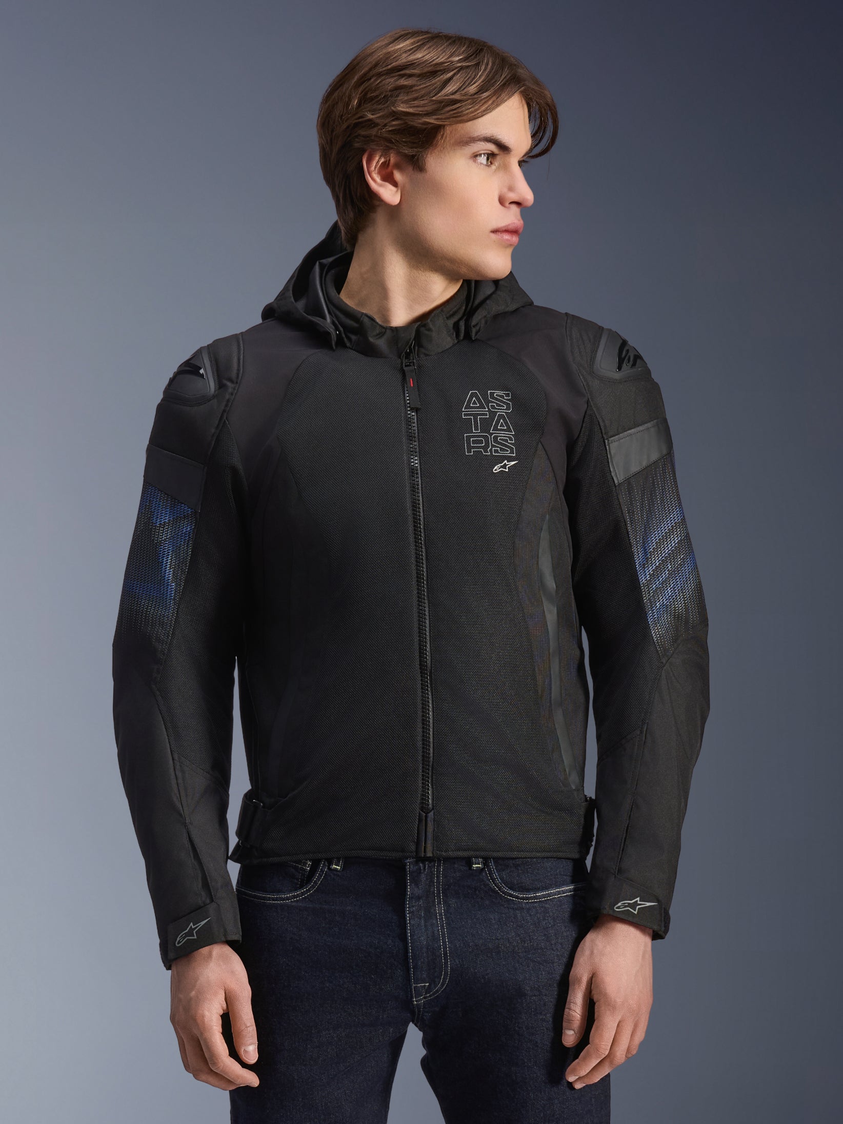 Alpinestars Zaca Air Venom WP Jacke, Schwarz und Electric Blue, Textil-Motorradjacke mit abnehmbarer Kapuze und 3D-Mesh-Einsätzen zur Belüftung, verfügt über DFS Lite Schultergleiter und ASTARS-Branding auf der Brust, getragen von einem männlichen Modell, sportlich inspirierte urbane Fahrausrüstung