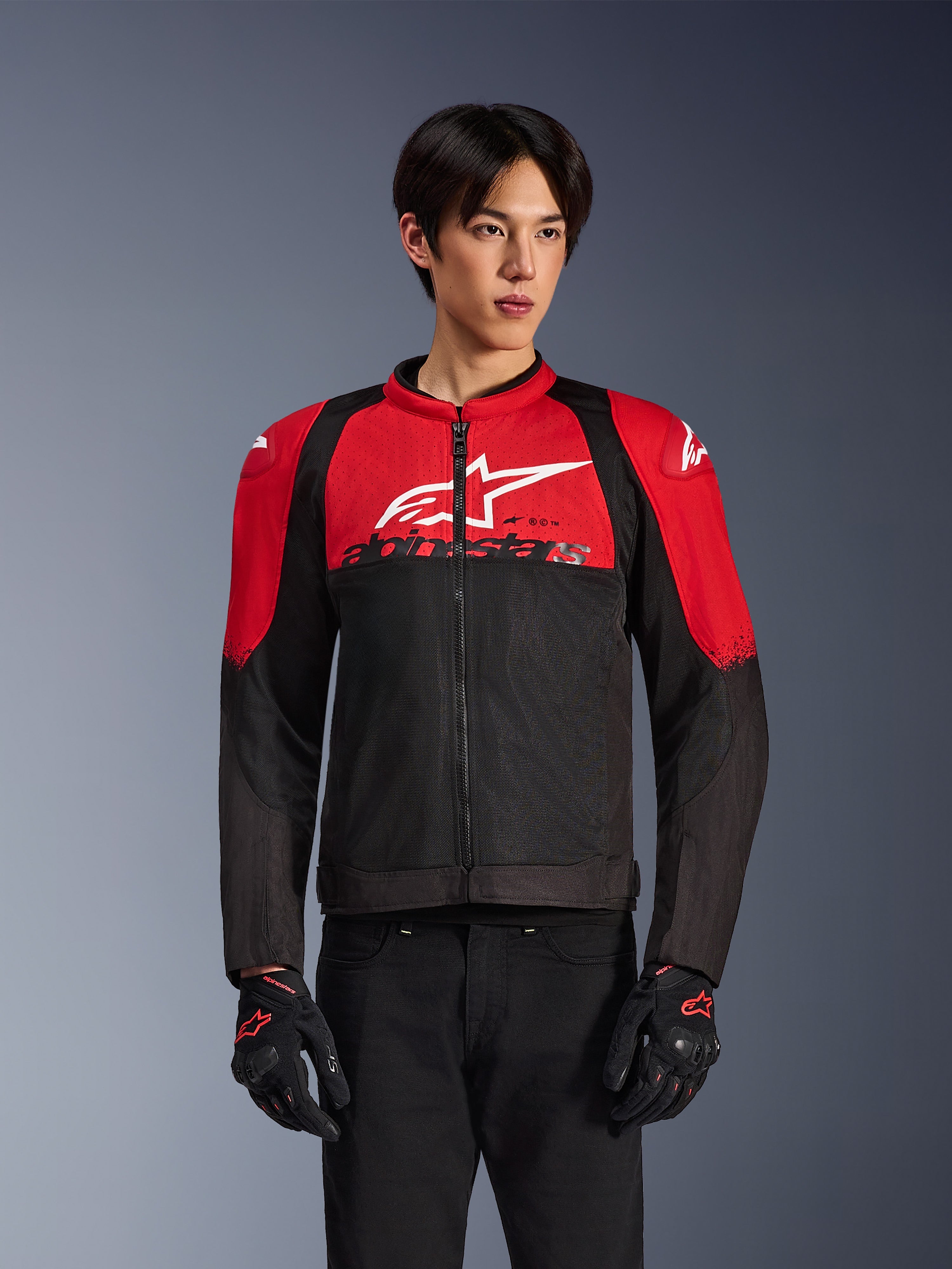 Alpinestars SMX Air Jacket, Motorcycle Mesh Jacket, Bright Red and Black, worn by a model with black riding gloves, featuring a large white logo on the chest, ventilated textile construction with red shoulder panels and black sleeves, sporty performance gear for warm-weather riding