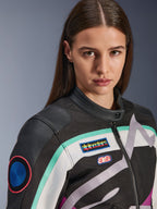 Alpinestars Idles Damenjacke, Motorradjacke, Schwarz, Off-White und Lila mit blaugrünen Akzenten, Nahaufnahme mit farbenfrohen Alpinestars Heritage-Aufnähern und Schulterdetails aus Ziegenleder, Vintage-inspiriertes Design für urbanes Fahren.