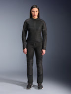 Frau trägt die Alpinestars Stella C-1 Air Jacke in Schwarz, kombiniert mit passender schwarzer Textil-Motorradhose und Motorradschuhen, mit einem eleganten urbanen Design und großen Mesh-Einsätzen für Luftzirkulation.