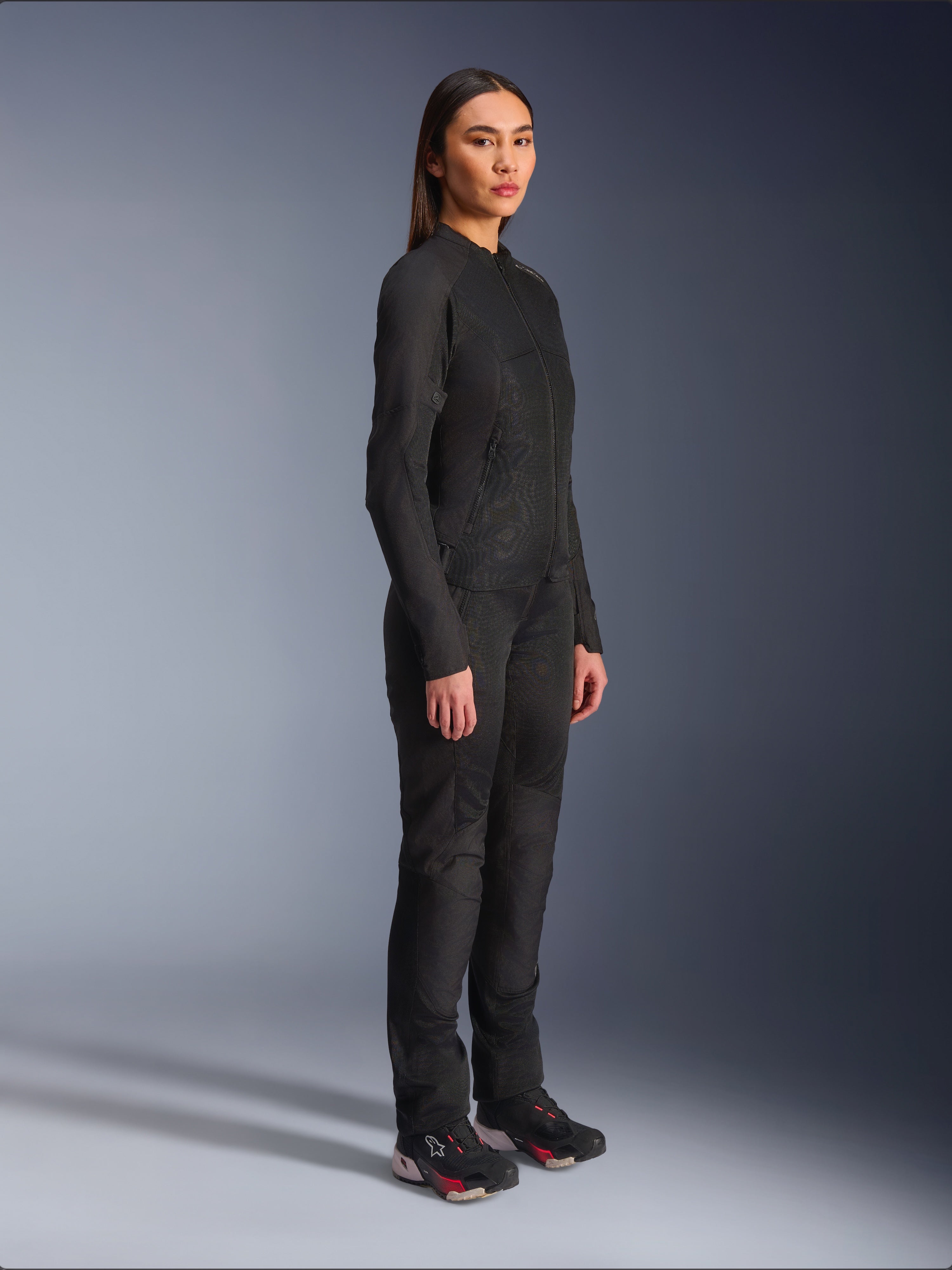 Alpinestars Stella C-1 Air Damenjacke in Schwarz, Textil-Motorradjacke mit Mesh-Einsätzen, kombiniert mit passender schwarzer Fahrhose und technischen Sneakern, Studioaufnahme eines kompletten urbanen Motorrad-Outfits.