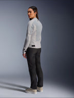Woman wearing Alpinestars Stella C-1 Air Jacket in Silver, back and side view showing tech mesh panels and reflective shoulder logo, paired with black motorcycle pants and beige sneakers, contemporary urban riding aesthetic
