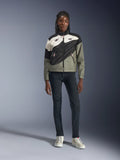 Alpinestars Stella Moshell Jacke, Damen-Motorradjacke, Schwarz, Pelzgrau und Off-White mit pinken Akzenten, getragen von einem Modell mit dunkler Jeans und cremeweißen Sneakern, asymmetrisches Reißverschluss-Design mit markanten geometrischen Grafiken, moderne urbane Motorradbekleidung