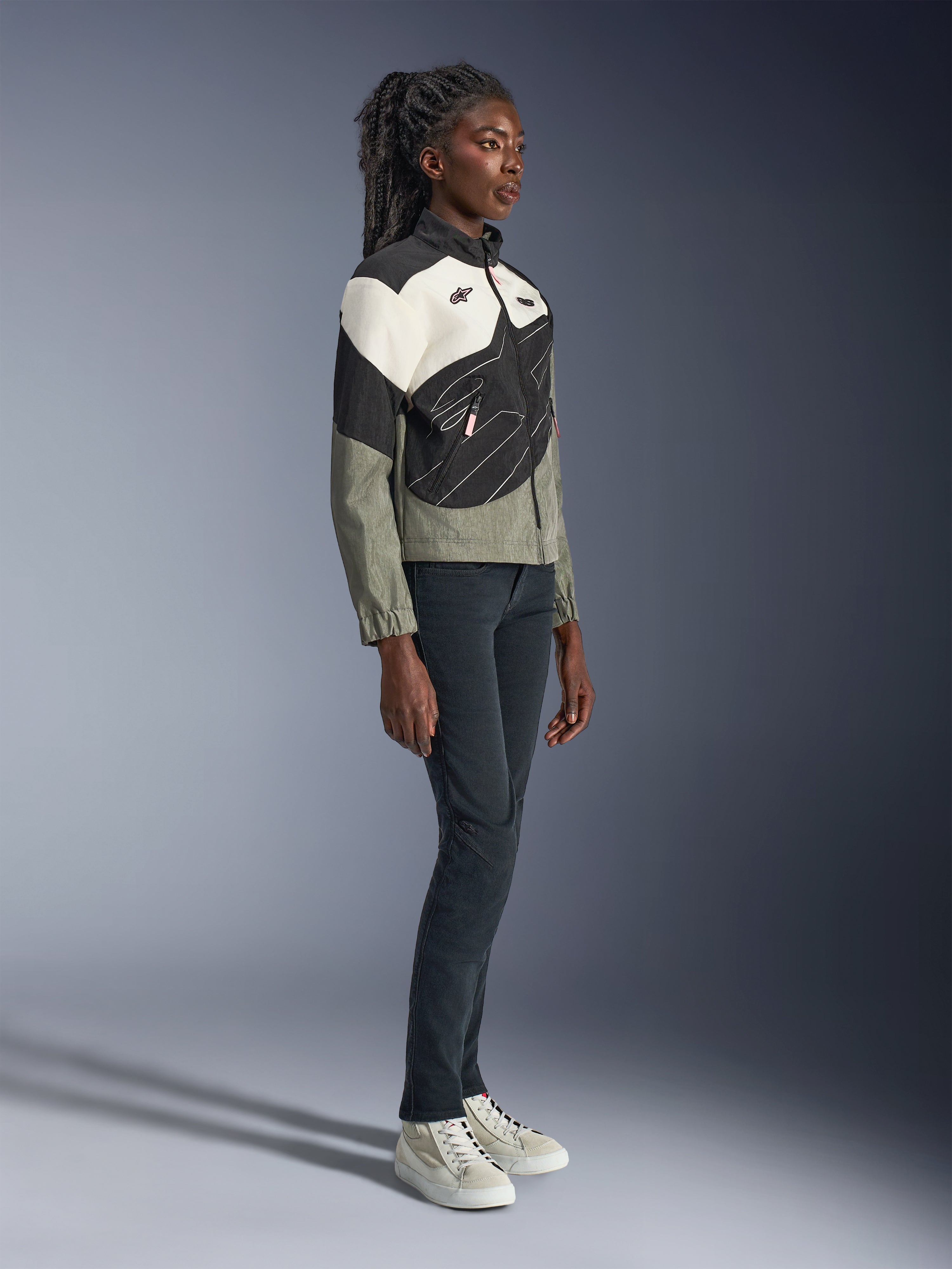 Alpinestars Stella Moshell Jacke, Urban Motorradjacke für Damen, Grau, Schwarz und Off-White mit rosa Akzenten, Ganzkörperansicht eines weiblichen Modells in dunkler Hose und Sneakern, modernes, von Streetwear inspiriertes Design für urbanes Fahren
