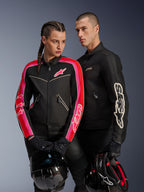 Alpinestars Stella T-Dyno Air Jacke für Damen in Schwarz, Bright Red und Fuchsia, kombiniert mit der schwarzen Dyno Air Jacke für Herren, beide Fahrer halten Motorradhelme, Studioaufnahme moderner Urban-Motorradbekleidung