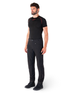 Alpinestars Alden Hose, Urbane Motorradhose, Schwarz, Softshell-Textil in regulärer Passform, getragen von einem Model mit schwarzem Base-Layer und Motorradschuhen, mit Taillengürtel mit Magnetverschluss und Reißverschlusstaschen.