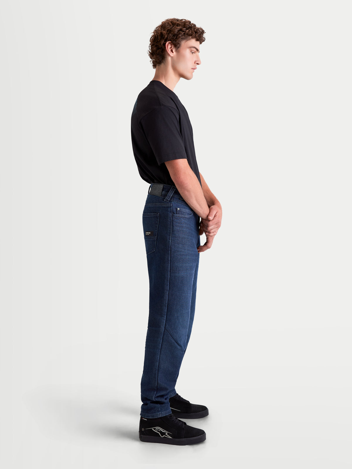 Alpinestars Flex-AST 10 Tough Max Denim Pants Short, men's urban contemporary motorcycle denim pants in dark blue, side profile view on a model wearing protective riding jeans with AAA certification and single-layer stretch construction