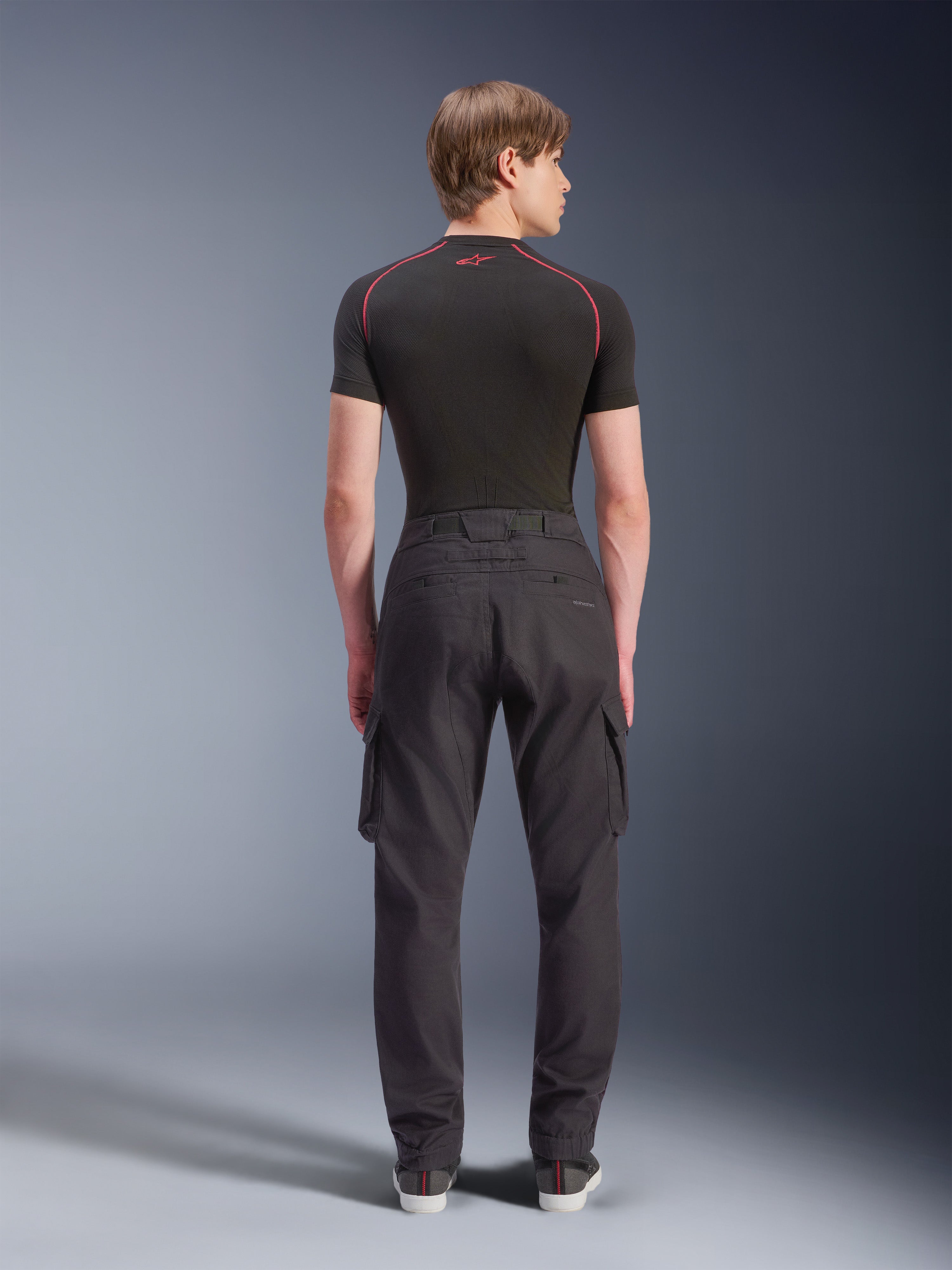 Alpinestars Flex-AST Cargo Pants - Short, Black, urban motorcycle pants shown from the rear, featuring side cargo pockets and elasticated hems, worn with a black short-sleeved base layer with red contrast stitching