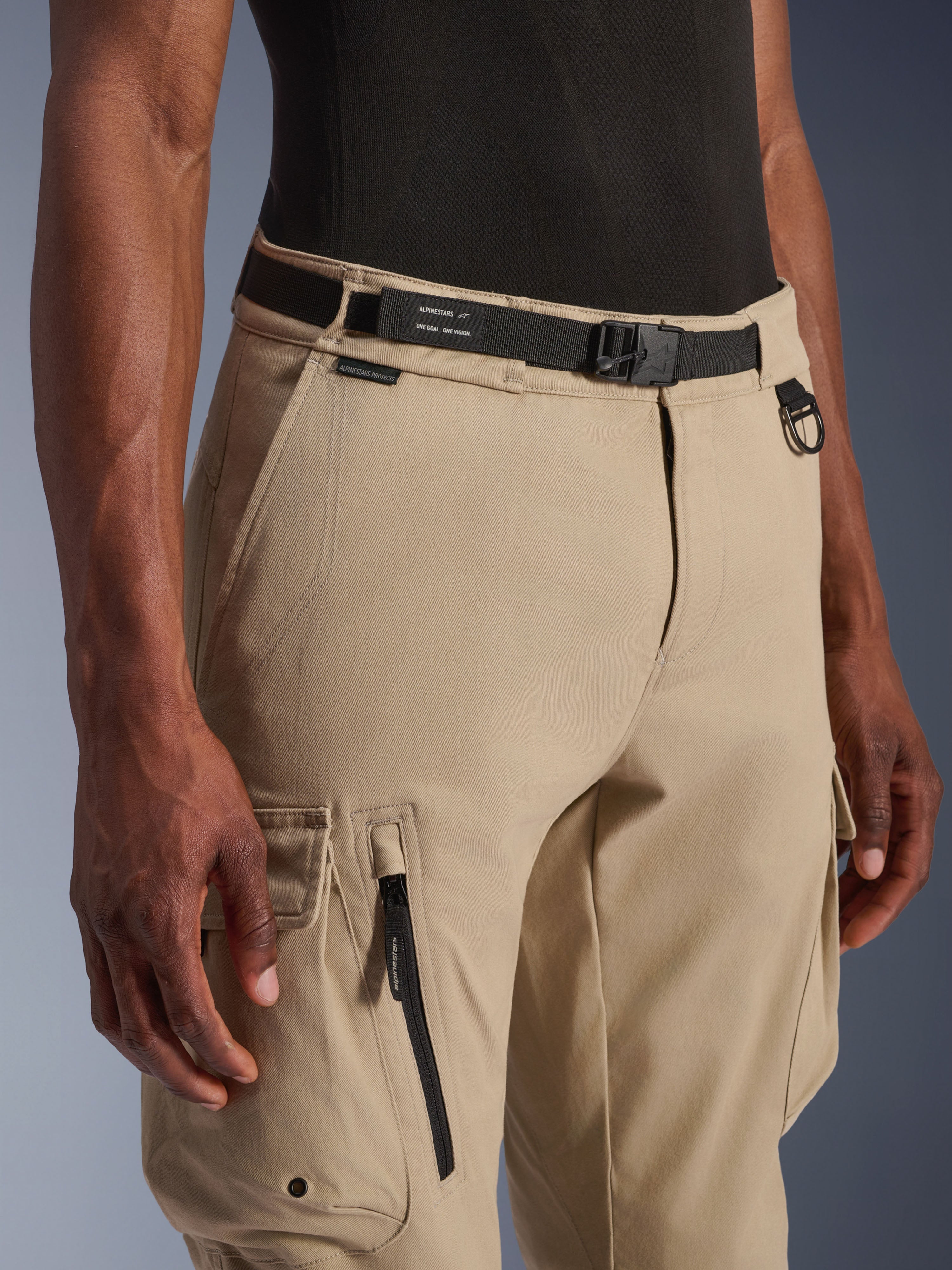 Alpinestars Flex-AST Cargo Pants, Motorcycle Cargo Pants, Light Beige, featuring an integrated black webbing belt with branding, metal D-ring, side zipper pocket, and durable twill fabric for a utilitarian urban riding look