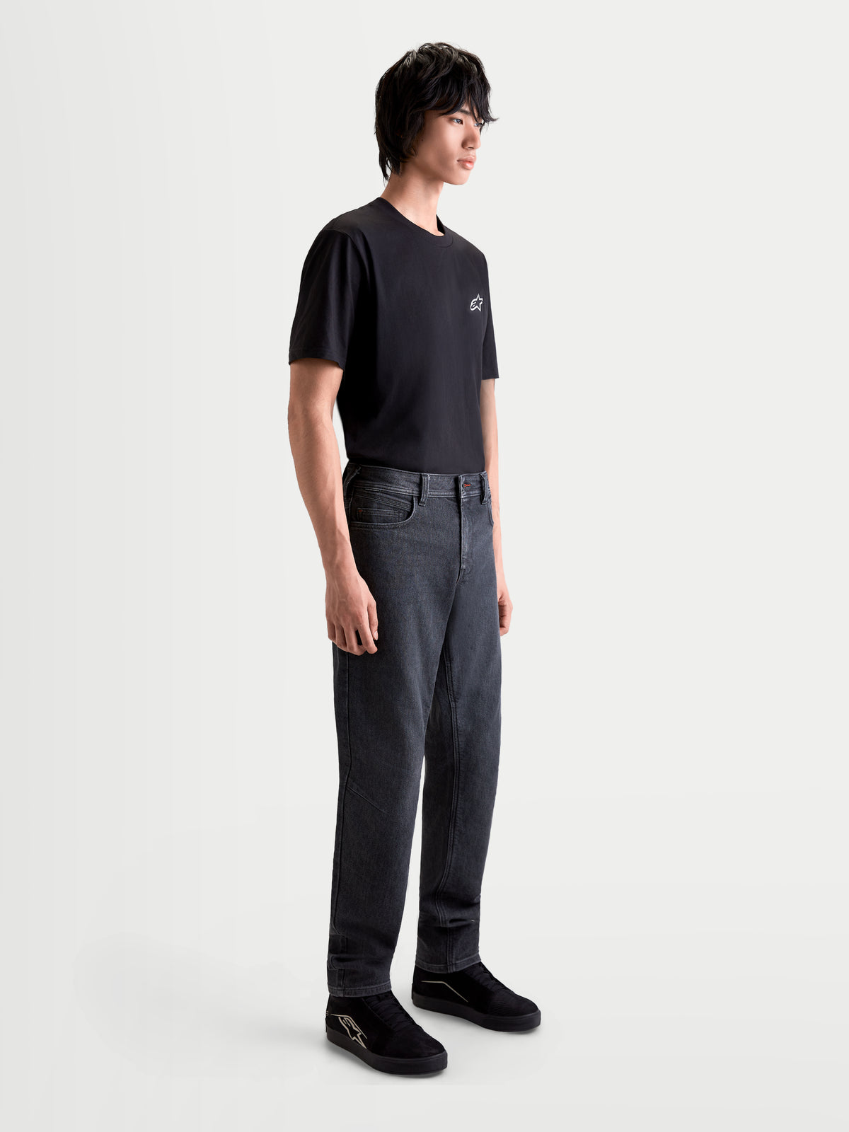 Alpinestars Flex-AST 7 Denim Pants, men's urban contemporary motorcycle riding jeans in faded black, side profile view on a model wearing a black t-shirt and shoes, AA-certified single-layer technical denim construction.