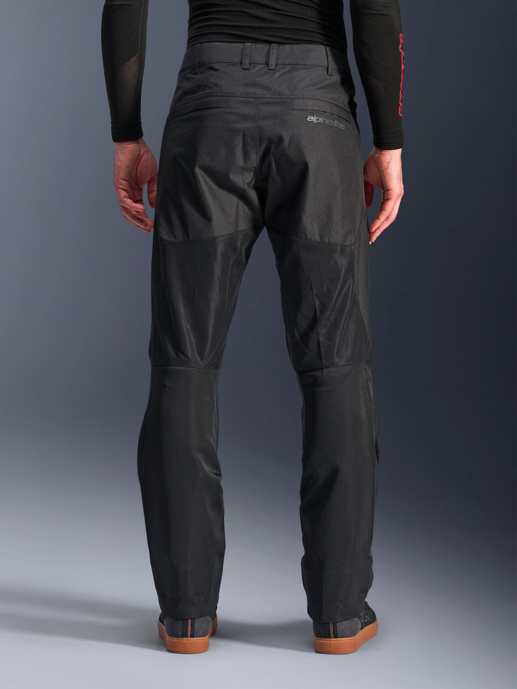 Alpinestars C-1 Air Hose, Rückansicht, Schwarz, urbane Textil-Motorradhose mit großen Tech-Mesh-Einsätzen an der Beinrückseite zur Belüftung, schlichtes Design mit dezentem Branding, getragen mit einem schwarzen Base-Layer und lässigen Fahrerschuhen.