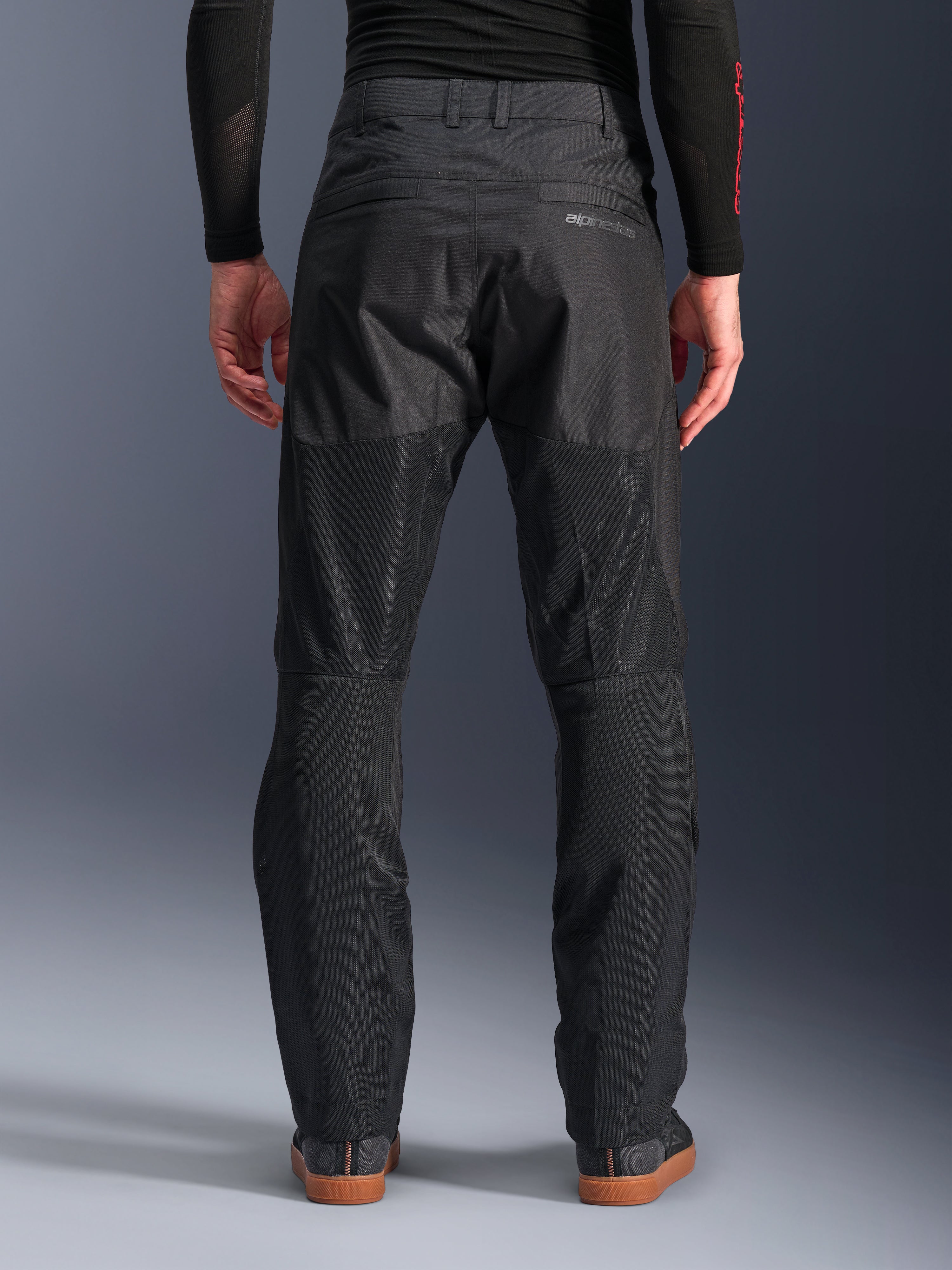 Alpinestars C-1 Air Hose, Rückansicht, Schwarz, urbane Textil-Motorradhose mit großen Tech-Mesh-Einsätzen an der Beinrückseite zur Belüftung, schlichtes Design mit dezentem Branding, getragen mit einem schwarzen Base-Layer und lässigen Fahrerschuhen.