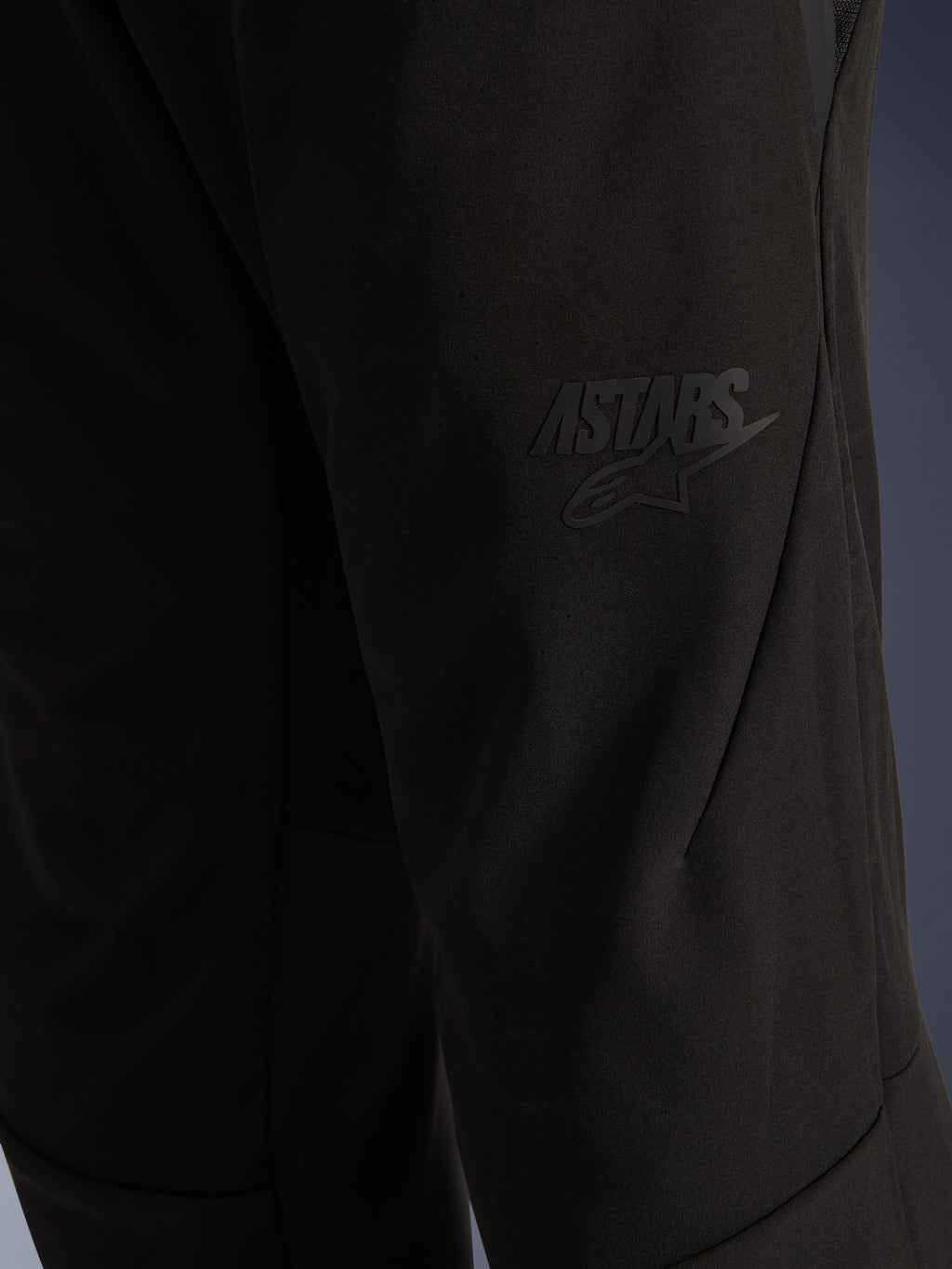 Alpinestars Aeroshell Airflow Pants, Black Motorcycle Pants, close-up view of the thigh area featuring a raised black ASTARS logo, lightweight stretch softshell material with ergonomic seam design