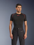 Male model wearing Alpinestars Flex-AST Canvas Pants in Black, urban motorcycle pants featuring visible zippered front pockets and a workwear-inspired design, paired with a black base layer with red accents.