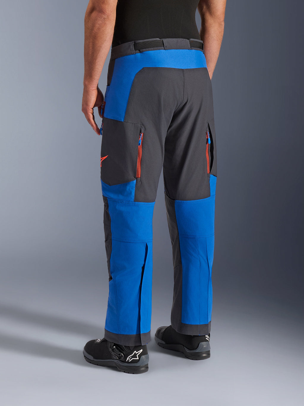 Alpinestars Maxdura Dual Pants, Royal Blue and Deep Gray, rear view showing zippered pockets and ventilation zones, over-boot design worn with black Alpinestars boots, durable adventure and dual-sport riding gear