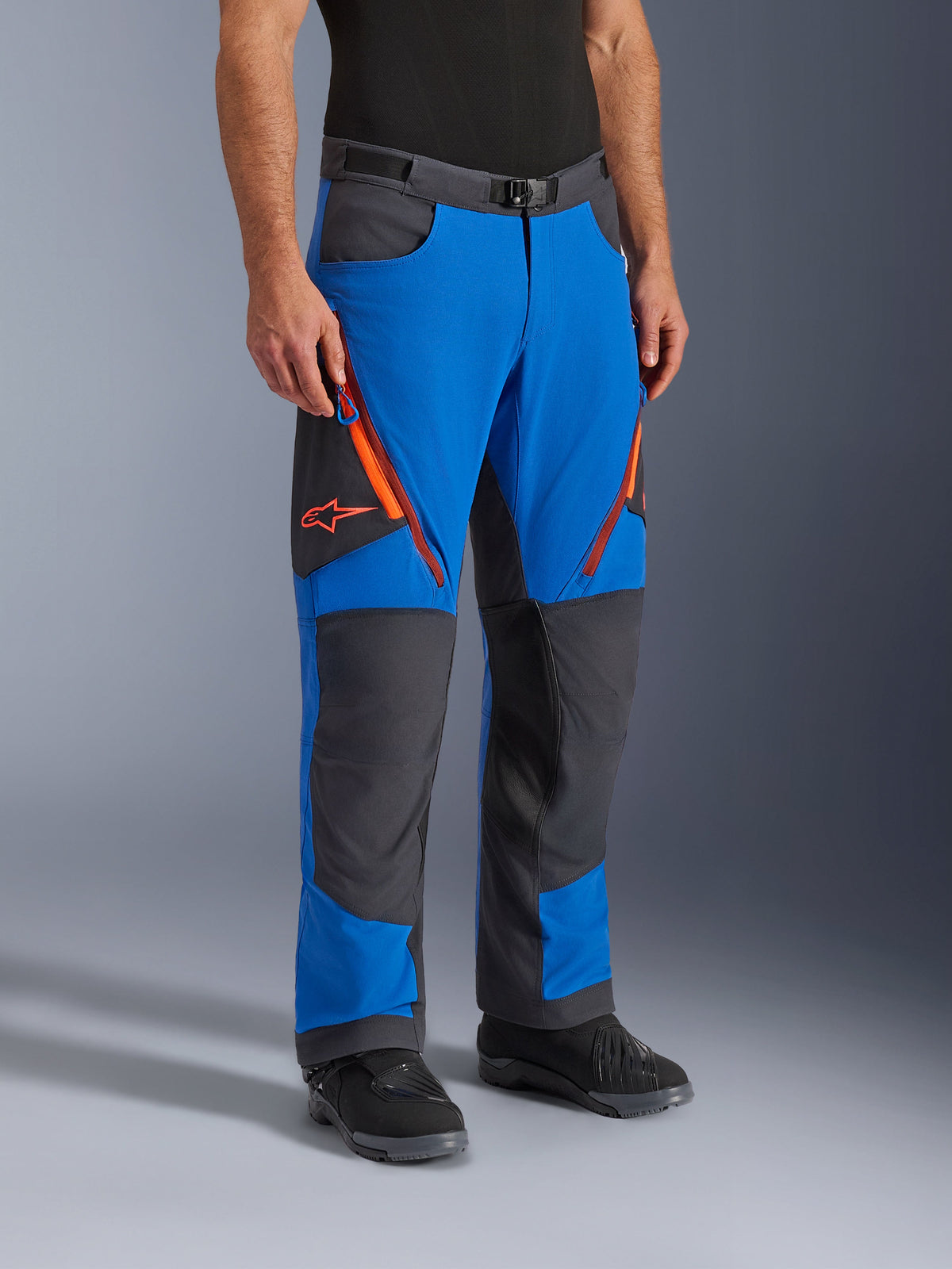 Alpinestars Maxdura Dual Pants, Adventure-Motorradhose, Königsblau und Dunkelgrau mit orangen Akzenten, mit Oberschenkelbelüftungen mit Reißverschluss, verstärkten Kniepaneelen und einem Gürtel mit Magnetschnalle, technisches Über-Stiefel-Design für Dual-Sport-Fahrten.