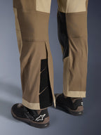 Alpinestars Maxdura Dual Hose in Walnut Aluminum, Detailansicht von Unterschenkel und Saum mit Über-den-Stiefel-Design, verstellbare Klettverschlüsse und verstärkte Innenpaneele, kombiniert mit schwarzen Motorradstiefeln.