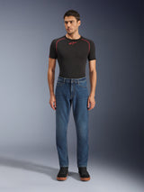 Alpinestars Flex-AST 5 Denim-Hose, Motorrad-Jeanshose, Indigo Washed, getragen mit schwarzem Performance-T-Shirt und schwarzen Sneakern, mit schmal zulaufender Passform und Monolayer-Stretch-Denim-Konstruktion für urbane Fahrten