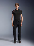 Alpinestars Copper V3 Denim Hose in Black Rinse, reguläre, bequeme Passform mit geradem Bein, getragen von einem männlichen Model mit einem schwarzen Baselayer-T-Shirt mit roten Kontrastnähten und schwarzen Motorrad-Sneakern, urbanes Motorrad-Outfit