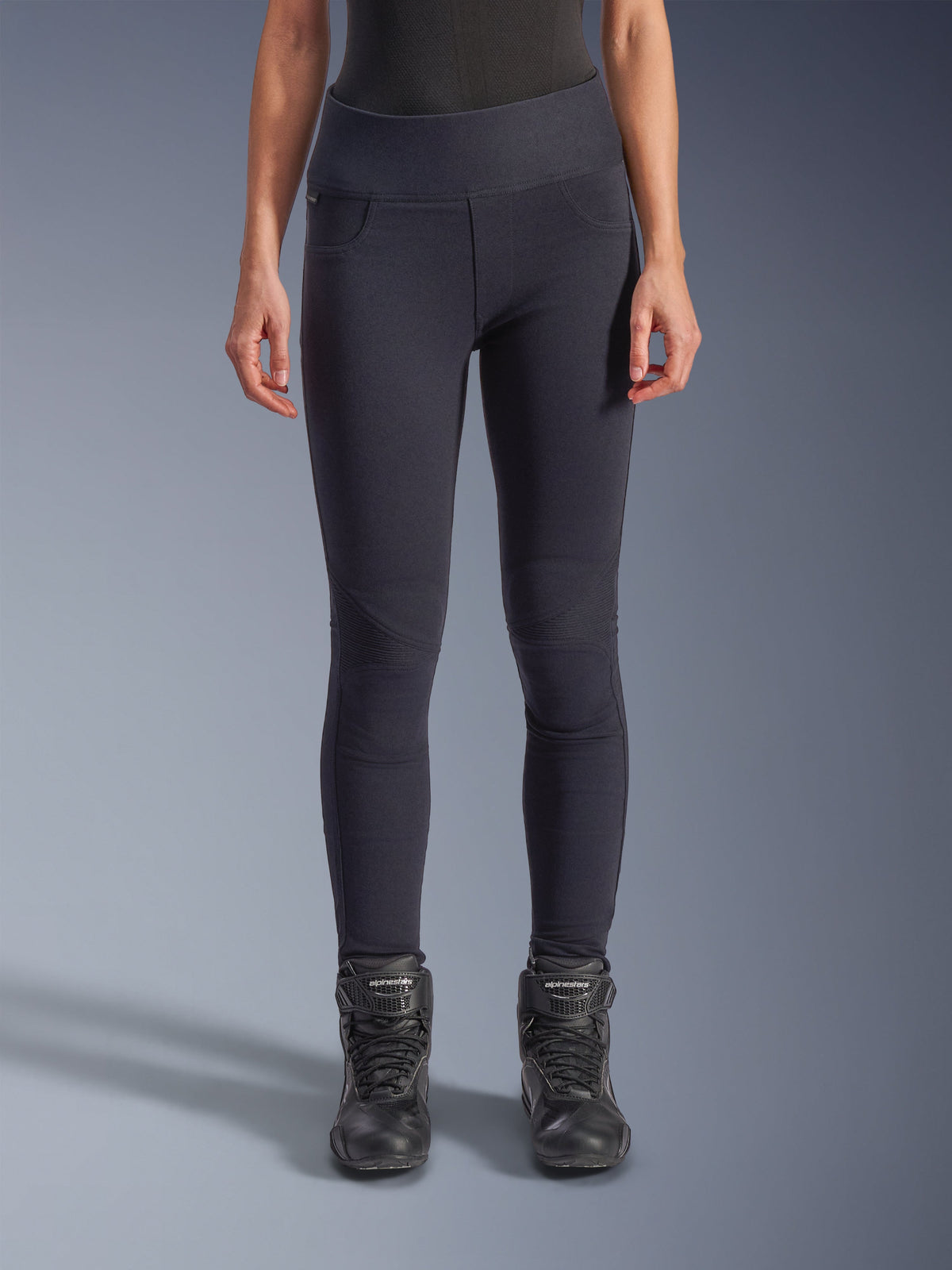 Alpinestars Stella Flex-Ast Leggings, Damen-Motorrad-Leggings, Schwarz, High-Waist-Passform mit artikulierten Kniepartien und konturierten Nähten, von Model mit schwarzen Motorradstiefeln getragen, urbane Performance-Fahrausrüstung