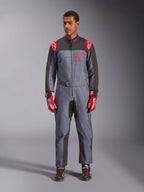 Alpinestars KMX-9 V3 Graphic 6 Anzug, Kart-Anzug, Anthrazit-Schwarz und Rot, grau gesprenkeltes Grafikmuster, schwarze Einsätze an den Innenseiten von Armen und Beinen, rote Alpinestars-Logos auf Schultern und Brust, getragen mit roten Rennhandschuhen und schwarzen Schuhen