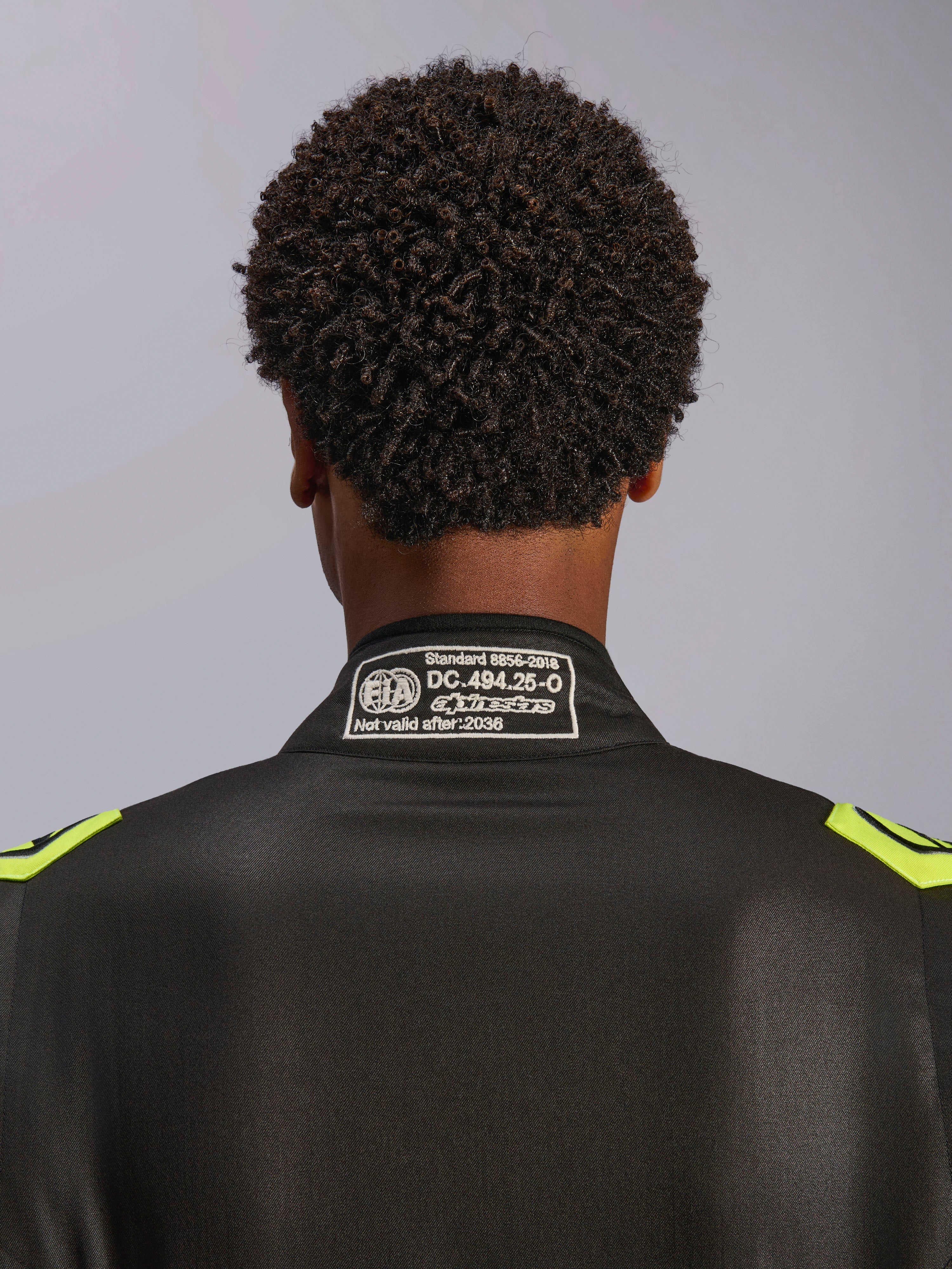 Alpinestars GP Race V3 Suit FIA, Black and Yellow Fluo, close-up of the back collar showing the FIA 8856-2018 certification label, professional automotive racing suit.