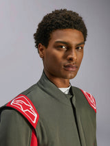 Alpinestars GP Race V3 Anzug FIA, Autorennanzug, Anthrazit-Rot, Nahaufnahme des Oberkörpers und Kopfes, mit roten Schulter-Epauletten mit weißem Alpinestars-Logo, hohem Kragen und grauem Twill-Material