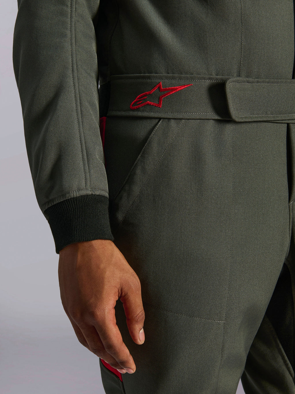 Alpinestars GP Race V3 Anzug FIA, Auto-Rennanzug, Anthrazit-Rot, Nahaufnahme des verstellbaren Gürtelbunds mit rot besticktem Logo und schwarzem geripptem Ärmelbündchen auf strukturiertem Twill-Gewebe