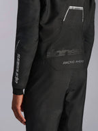 Nahaufnahme des Alpinestars Hypertech V3 Anzugs in Schwarz/Dark Shadow, zeigt Rückengrafiken „RACING AHEAD“ und „HYPERTECH V3“ sowie weißes Logo-Branding am Ärmel, professionelle Autorenn-Ausrüstung.